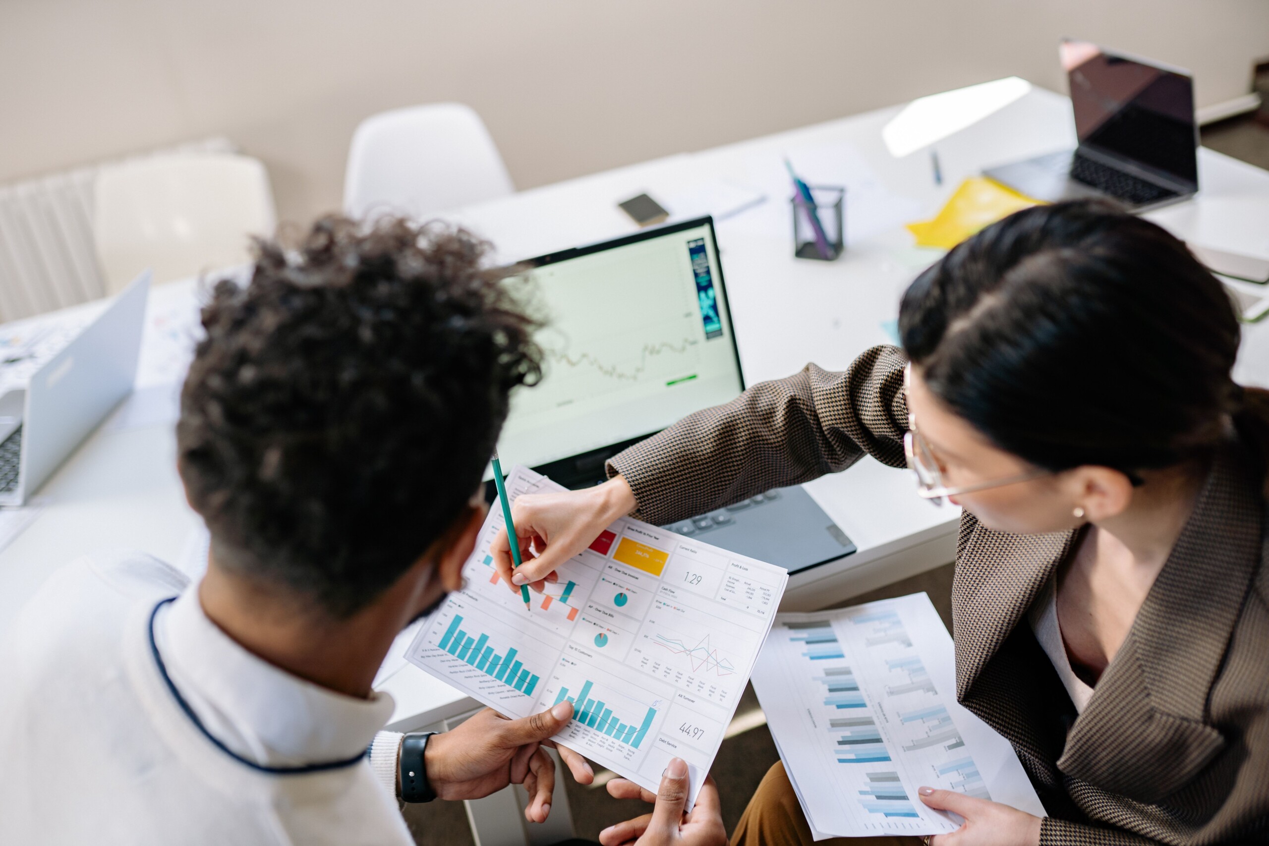 Two business colleagues reviewing financial charts and graphs during a meeting.